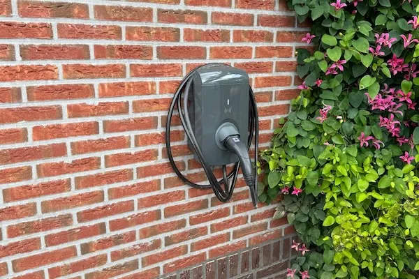 Laadpaal aan een bakstenen muur met laadkabel